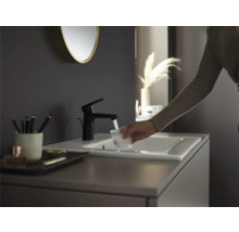 Scène de salle de bain moderne avec robinet noir, lavabo et personne remplissant un verre d''eau