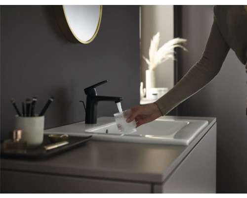 Moderne Badezimmerszene mit schwarzer Armatur, Waschbecken und Person, die ein Glas Wasser füllt