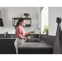 Une femme remplit d''eau un pichet à l''aide d''un robinet de cuisine dans la cuisine