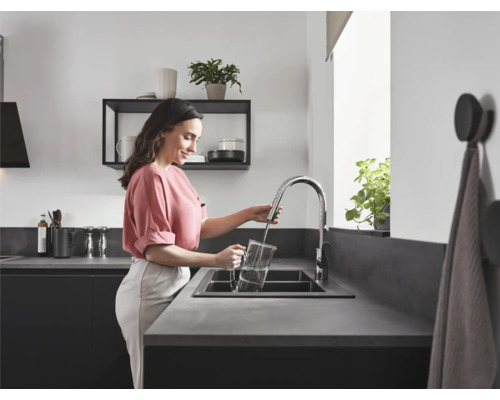 Une femme remplit d''eau un pichet à l''aide d''un robinet de cuisine dans la cuisine