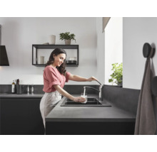 Femme remplissant un verre d''eau à l''évier de cuisine avec robinet.