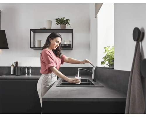 Femme remplissant un verre d''eau à l''évier de cuisine avec robinet.
