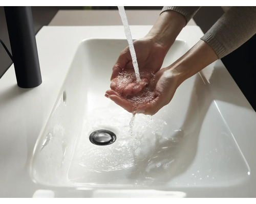 Hände werden in einem weißen Waschbecken mit Wasser gewaschen