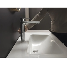 Une femme actionne le robinet du lavabo dans la salle de bain.