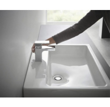 Main sur robinet chromé au-dessus d''un lavabo blanc