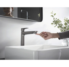 Waschbecken mit Armatur und berührender Hand im Badezimmer