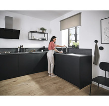 Cuisine moderne avec armoires noires, évier et robinet, hotte aspirante, étagère et une femme remplissant un verre d''eau.