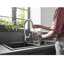 Une femme remplit un pichet d''eau dans un évier de cuisine