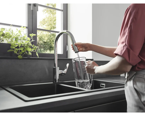 Une femme remplit un pichet d''eau dans un évier de cuisine