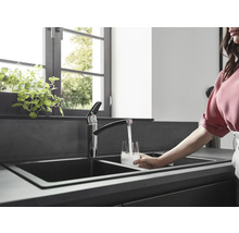 Scène de cuisine avec évier double, robinet et personne remplissant un verre d''eau