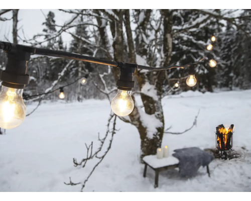 Guirlande lumineuse avec ampoules dans un jardin enneigé