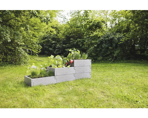 Jardinière surélevée en plastique avec plantations dans le jardin