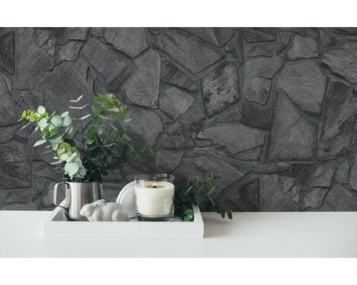 Mur en pierre décoratif avec plantes, bougie et objets décoratifs sur un plateau