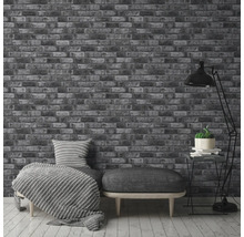 Intérieur avec un papier peint imitation briques, un canapé avec coussins et un lampadaire