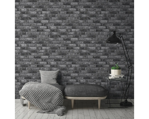 Intérieur avec un papier peint imitation briques, un canapé avec coussins et un lampadaire