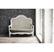 Sofa ancien avec cadre en bois et rembourrage devant un mur en pierre