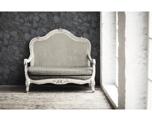 Sofa ancien avec cadre en bois et rembourrage devant un mur en pierre