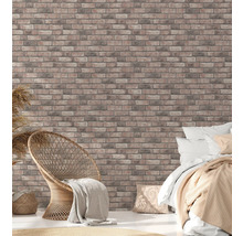 Chambre claire avec papier peint imitation briques, fauteuil en rotin et lit