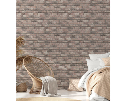 Chambre claire avec papier peint imitation briques, fauteuil en rotin et lit