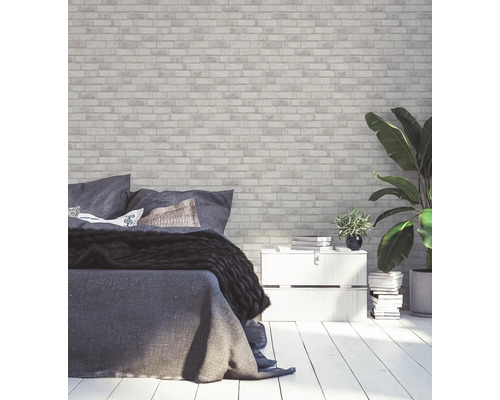 Chambre avec papier peint en briques, lit et plantes