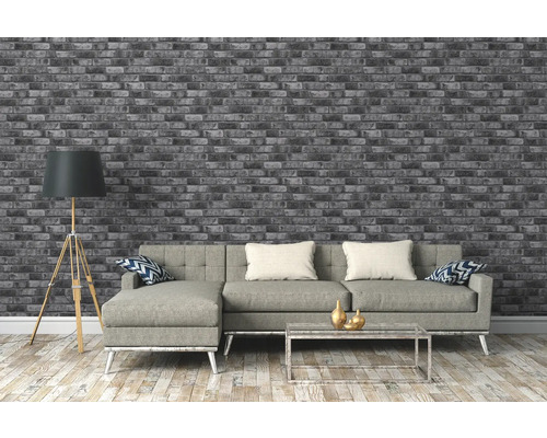 Salon avec papier peint briques gris, canapé, lampadaire et table basse