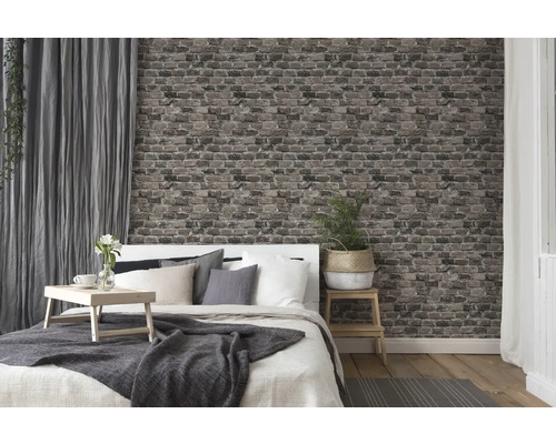 Chambre avec lit, table de chevet, rideaux et papier peint imitation brique pour une ambiance chaleureuse