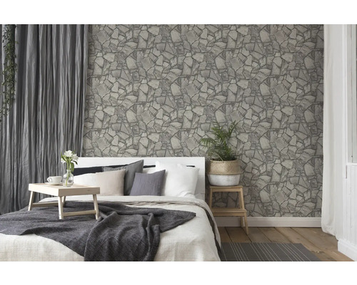 Chambre à coucher avec lit devant un papier peint à motif de pierres.