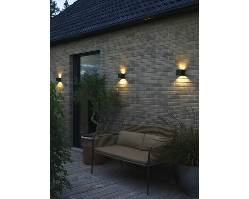 Extérieur avec mur, banc et appliques murales.