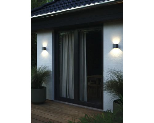 Mur de maison avec deux appliques murales extérieures carrées, porte de patio et pots de fleurs