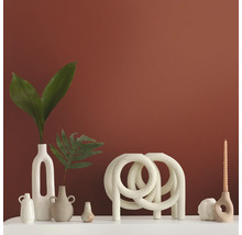 Dekorative Vasen und Kerzenständer auf einer weißen Oberfläche vor einer farbigen Wand