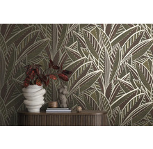 Raum mit einer Wandtapete mit Blattmuster, einem Holztisch und dekorativen Gegenständen.