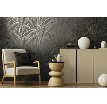 Wohnraum mit Sessel, Beistelltisch und Schrank vor einer gemusterten Tapete.