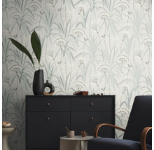 Ein Raum mit einer gemusterten Tapete mit floralem Design, einer Kommode und einem Sessel.