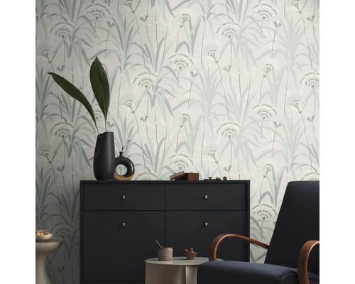 Ein Raum mit einer gemusterten Tapete mit floralem Design, einer Kommode und einem Sessel.