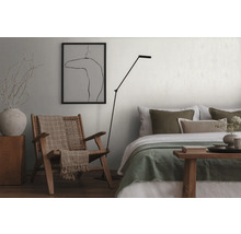 Wohnzimmer mit Sessel, Stehlampe und Bett