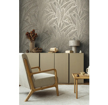 Wohnzimmer mit Blättertapete, Sessel, Kommode und Beistelltisch