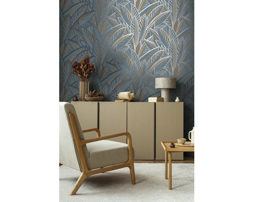 Wohnzimmer mit gemusterter Tapete mit Blattmotiven, Sessel, Kommode und Tisch