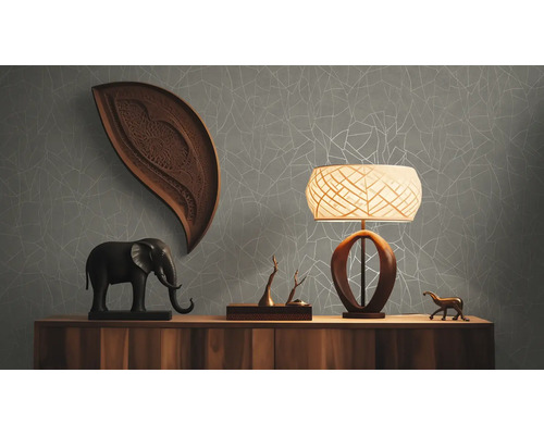 Wohnraum mit Kommode, Lampe und Dekorationen vor einer grauen Tapete mit Muster