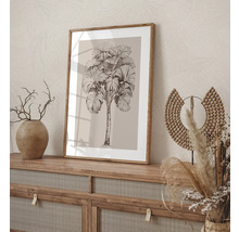 Dekoratives Bild mit einem Palmenmotiv in einem Holzrahmen, platziert auf einem Sideboard.