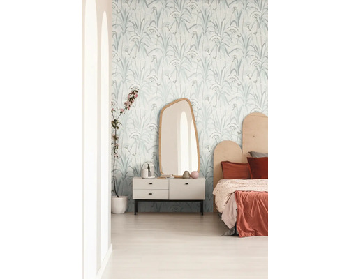 Helles Schlafzimmer mit Tapete mit Pflanzenmuster, Spiegel und Kommode.