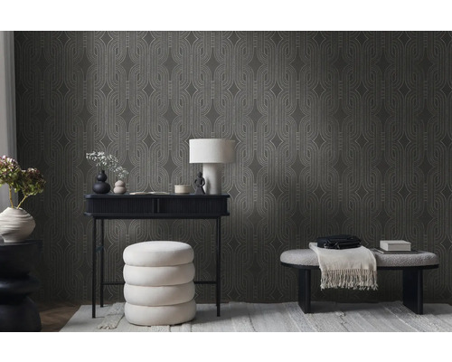 Wohnzimmer mit gemusterter Tapete, Schreibtisch, Lampe und Sitzgelegenheiten.