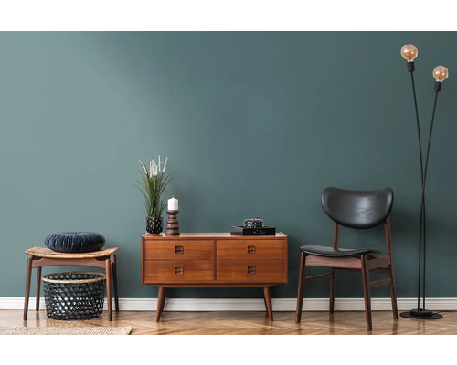 Wohnzimmer mit Holzkommode, Stuhl, Hocker und Stehlampe auf Parkettboden