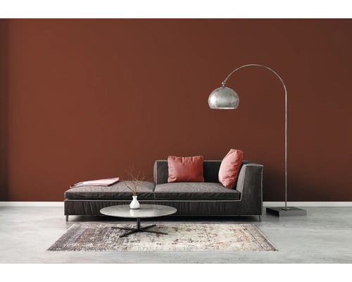 Wohnzimmer mit Sofa, Stehlampe und Teppich auf Betonboden vor brauner Wand