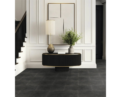 Hall d''entrée avec sol foncé, table, lampe et escalier