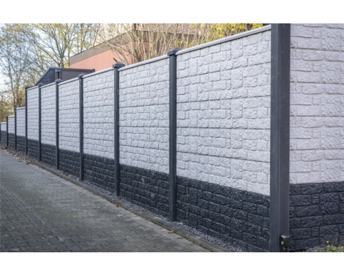 Un long mur antibruit gris avec des poteaux délimite une propriété.