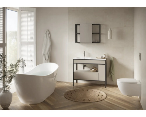 Badezimmer mit Badewanne, Waschtisch, Spiegel, Toilette und Teppich auf Holzboden.