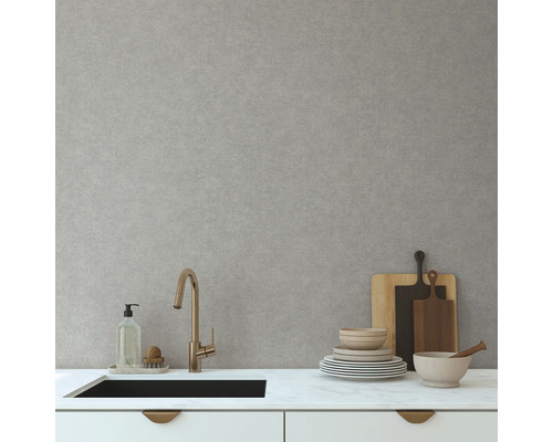 Scène de cuisine avec évier, robinet, vaisselle et planches à découper devant un mur gris clair