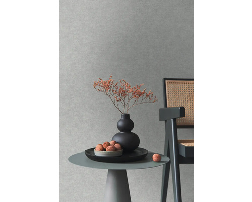 Scène décorative avec table, vase, fleurs séchées et chaise devant un mur texturé