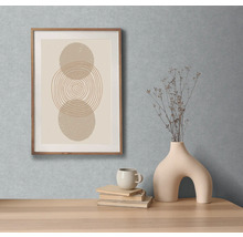 Scène décorative avec un tableau abstrait encadré, un vase, une tasse et des livres sur une table