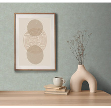 Image décorative avec des formes géométriques dans un cadre en bois, avec un vase avec des branches, une tasse et des livres sur une table.